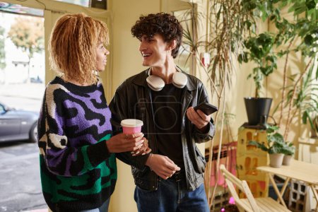 Foto de Alegre diversa pareja en traje casual mirándose mientras charlan en la cafetería vegana - Imagen libre de derechos