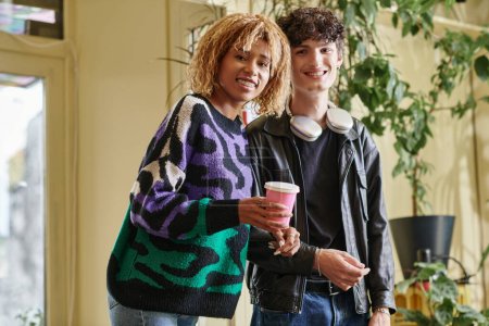 alegre y diversa pareja en traje casual mirando a la cámara mientras están de pie juntos en la cafetería vegana