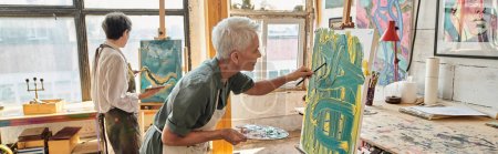 inspired mature women painting on easels in craft workshop with colorful pictures on walls, banner