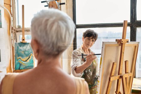 hábil artista mujer pintura borrosa modelo maduro en taller de arte, talento y creatividad