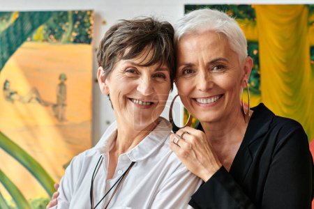 portrait d'artistes lesbiennes élégants et joyeux souriant à la caméra dans un atelier d'art contemporain