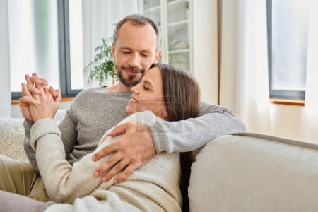 pleased child-free couple holding hands and embracing at home in living room, warm relationship