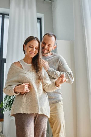 smiling man hugging happy wife in modern living room at cozy home, child-free modern lifestyle