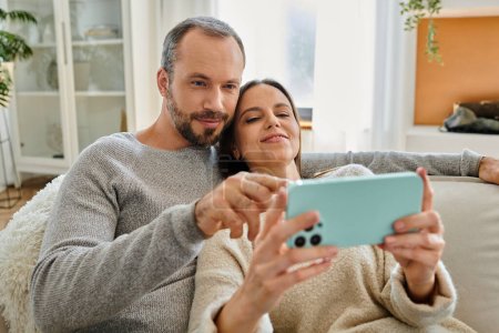 carefree child-free couple relaxing and browsing internet on mobile phone at home, quality time
