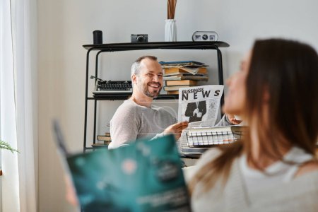 cheerful man with business newspaper smiling at wife with magazine, leisure of child-free couple