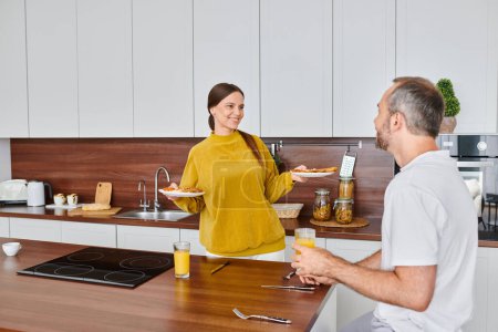 Photo for Happy woman holding delicious breakfast near husband with orange juice in kitchen, child-free life - Royalty Free Image