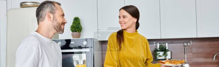 Téléchargez les photos : Femme souriante tenant la plaque avec petit déjeuner fait maison près mari heureux dans la cuisine moderne, bannière - en image libre de droit