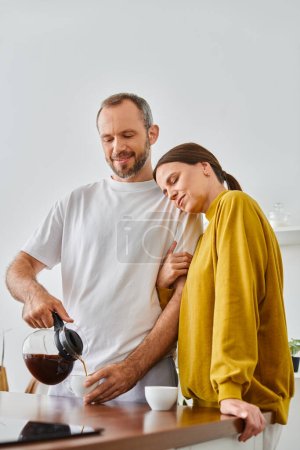 hombre cariñoso verter café aromático fresco cerca de esposa feliz en la cocina, mañana de pareja libre de niños