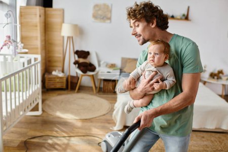 man multitasking housework and childcare, father vacuuming hardwood floor with baby son in arms