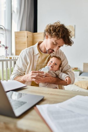 caring father holding baby bottle with milk and feeding infant son while working from home