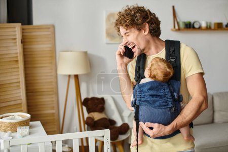 happy father talking on smartphone with baby sleeping in carrier, balance between life and work