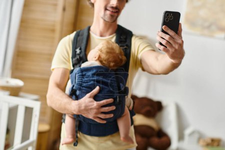 cropped father taking selfie with sleeping baby in carrier, fatherhood and modern parenting concept