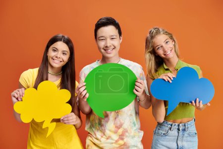 cheerful adolescent interracial boy and girls holding thought and speech bubbles, friendship day
