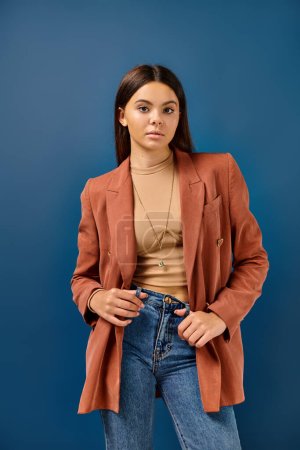 adorable stylish adolescent girl in brown elegant blazer posing and looking straight at camera