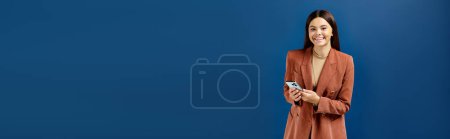 fröhliches, stilvolles Teenager-Mädchen im eleganten Blazer, Smartphone in der Hand und lächelnd in die Kamera, Banner