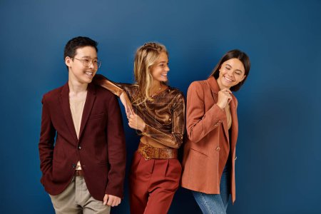 fröhlich stylische diverse Jugendliche in trendigen Anzügen lächeln glücklich auf blauem Hintergrund, Freundschaftstag