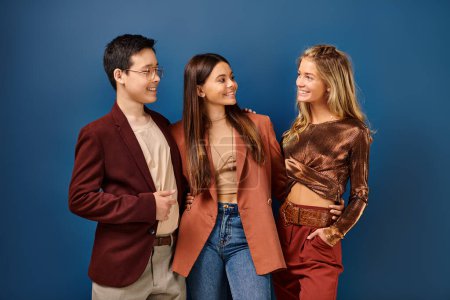 adorable jolly diverse teens in stylish vibrant clothes having fun on blue backdrop, friendship day