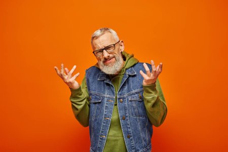 Photo for Confused good looking man in green vibrant hoodie and denim vest shrugging and looking at camera - Royalty Free Image