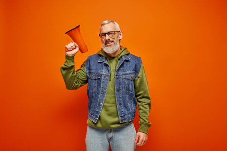 handsome jolly mature man in vibrant attire smiling at camera and holding megaphone in hand