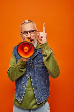 handsome mature male model in vibrant attire talking into megaphone and looking straight at camera