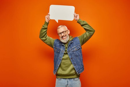 Photo for Cheerful handsome mature man in green hoodie holding speech bubble above head and smiling at camera - Royalty Free Image