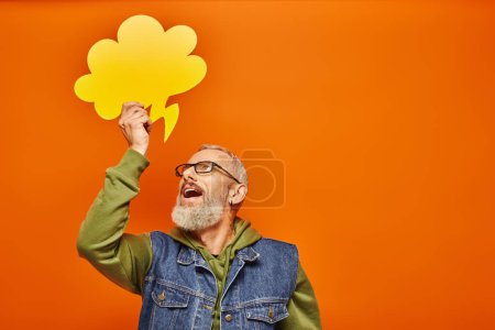 Photo for Joyous handsome mature man in denim vest holding thought bubble above his head and looking at it - Royalty Free Image