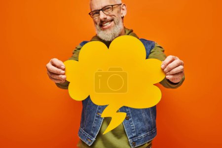 Photo for Focus on yellow thought bubble in hands of cheerful blurred mature man that looking at camera - Royalty Free Image