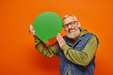 Photo for Handsome joyous mature man with glasses and beard holding speech bubble and posing with closed eyes - Royalty Free Image