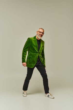 Foto de Fresco modelo masculino maduro alegre en chaqueta verde vivo con barba gris sonriendo sinceramente a la cámara - Imagen libre de derechos