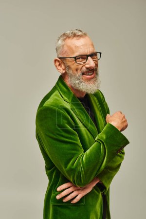 Photo for Cheerful handsome mature man in vibrant green blazer with beard and glasses smiling at camera - Royalty Free Image