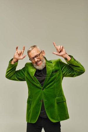 Photo for Good looking joyous mature man in vibrant attire posing with closed eyes showing rock sign - Royalty Free Image