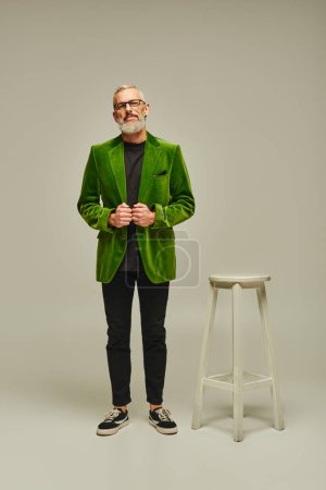 Photo for Handsome mature male model in stylish green blazer posing next to tall chair and looking at camera - Royalty Free Image