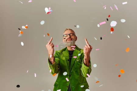 Photo for Good looking funky mature man in green blazer showing middle fingers at camera with closed eyes - Royalty Free Image