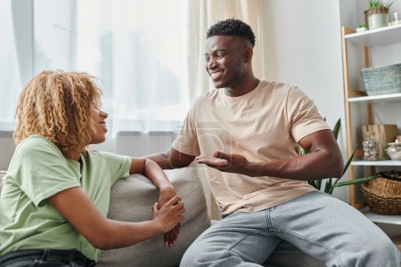 Téléchargez les photos : Heureux noir homme souriant tout en utilisant le langage des signes pour la communication avec petite amie dans les bretelles - en image libre de droit