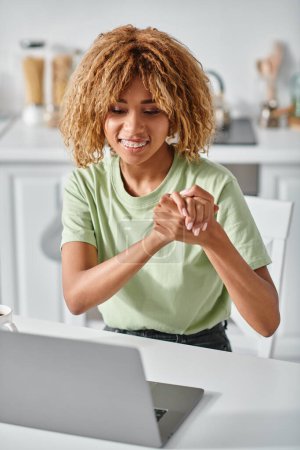 Téléchargez les photos : Heureux afro-américaine femme dans les bretelles en utilisant le langage des signes lors de l'appel vidéo sur ordinateur portable, geste - en image libre de droit
