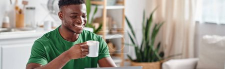 Lächelnder afrikanisch-amerikanischer Mann genießt eine Tasse Kaffee und lächelt in der Küche, horizontales Banner