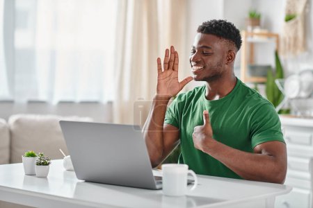 cheerful african american man communicating with sigh language during online meeting on laptop