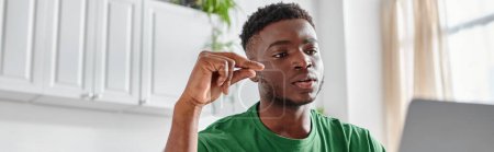 homme afro-américain concentré utilisant le langage des signes lors d'un appel vidéo sur ordinateur portable à la maison, bannière