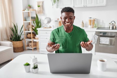 hombre sordo afroamericano positivo usando lenguaje de señas durante la videollamada en el ordenador portátil en casa