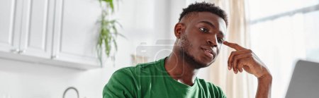 schöner und junger afrikanisch-amerikanischer Mann beobachtet Online-Webinar von Laptop zu Hause, Banner