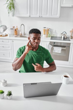 Téléchargez les photos : Homme afro-américain sourd en t-shirt vert utilisant le langage des signes pour la communication lors d'un appel vidéo - en image libre de droit
