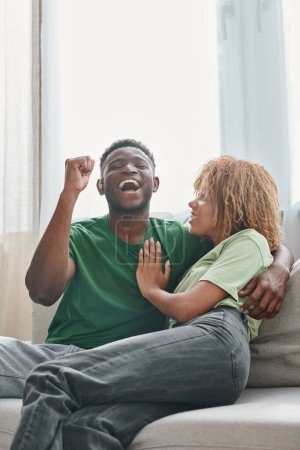 pareja afroamericana excitada, hombre negro sordo en audífonos abrazando a la mujer con aparatos ortopédicos