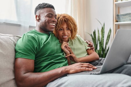 happy african american couple walking movie on laptop, deaf man in hearing air and woman in braces
