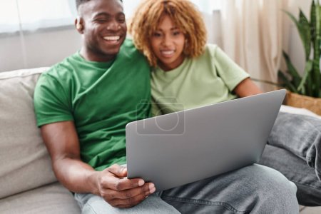 smiling black couple walking movie on laptop, deaf man in hearing air and woman in braces