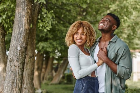 Photo for Cheerful african american couple holding hands and hugging each other outdoors, woman in braces - Royalty Free Image
