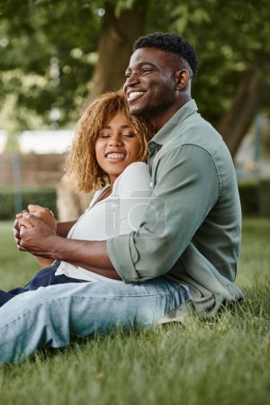 Téléchargez les photos : Heureux couple afro-américain passer du temps de qualité avec l'autre dans le parc, se tenant la main - en image libre de droit