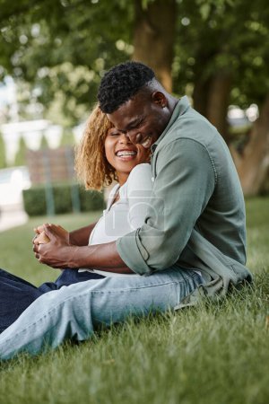 Téléchargez les photos : Positif couple afro-américain passer du temps de qualité avec l'autre dans le parc, se tenant la main - en image libre de droit