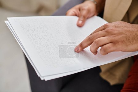 Photo for Cropped view of indian disabled man in casual attire sitting on sofa and reading braille code, blind - Royalty Free Image