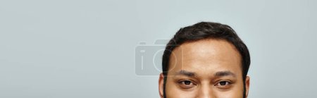 Photo for Handsome indian male model looking straight at camera with gray wall on background, banner - Royalty Free Image
