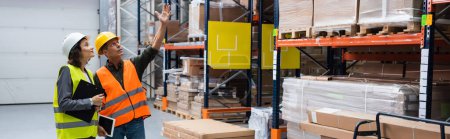 Photo for Banner of happy supervisor pointing out details to female employee in a warehouse with cargo - Royalty Free Image